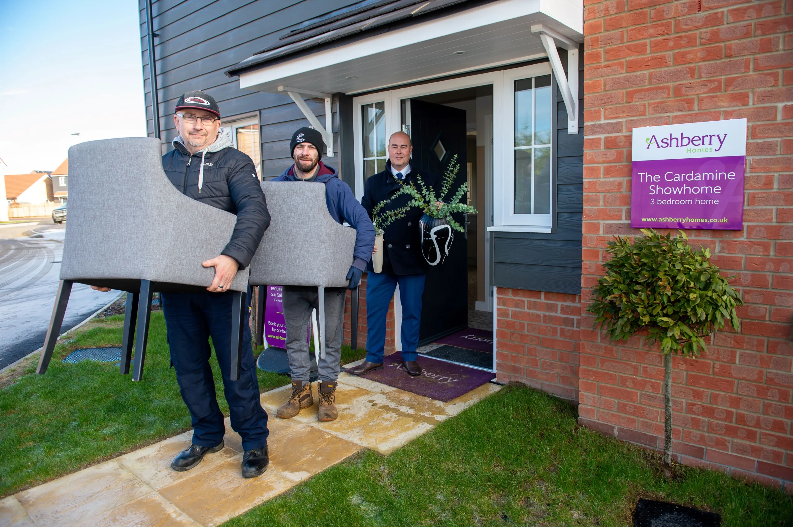 Darren Holloway and David Kelly from Emmaus Cambridge with sales advisor Stuart Burton from Ashberry Homes, outside the showhome at Cortlands in Fordham, with some of the furniture donated to the charity.